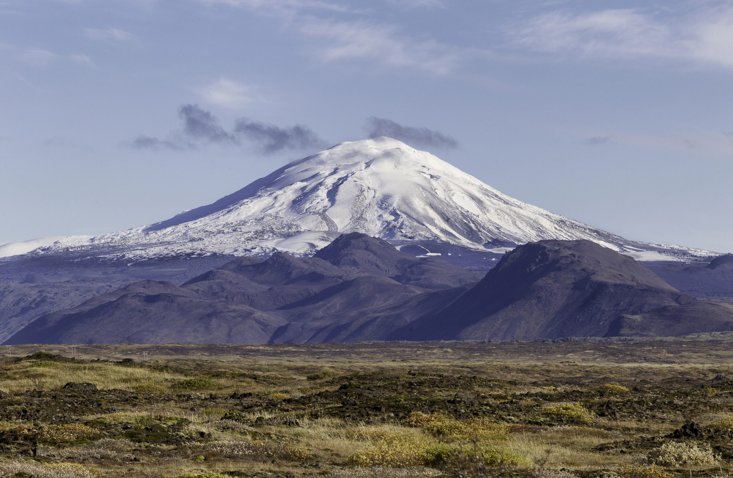 Hekla Volcano in Iceland, a majestic snow-capped stratovolcano with rugged terrain and volcanic landscapes under a clear blue sky.